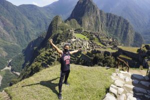 Person in the foreground on an upper terrace of Machu Picchu with Huayna Picchu mountain in the background